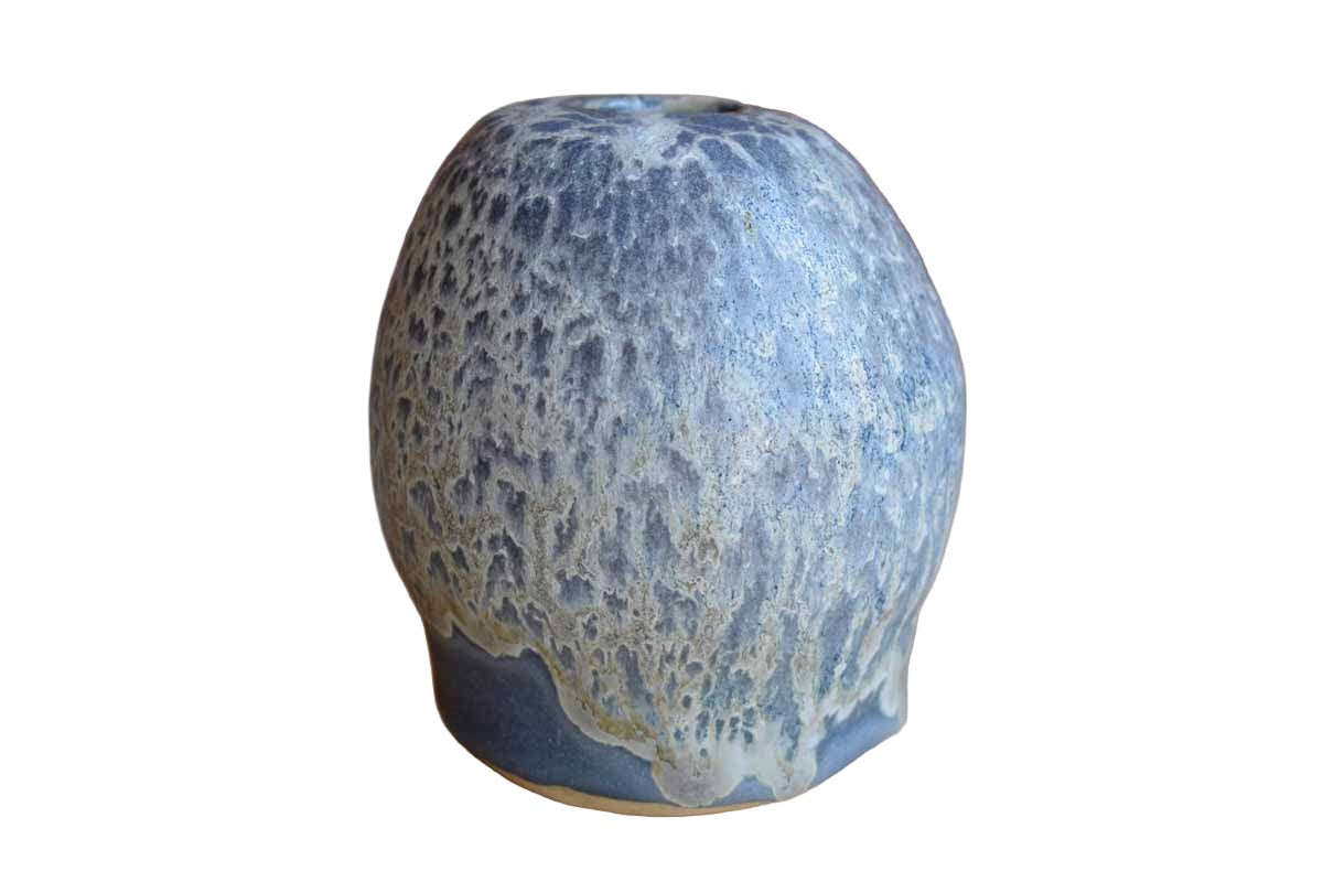 An interesting handmade stoneware vase featuring a simple, asymmetrical form finished with a purple and white lava glaze dripped imperfectly down the rounded sides. The bottom of the vase is signed and the overall condition is good.